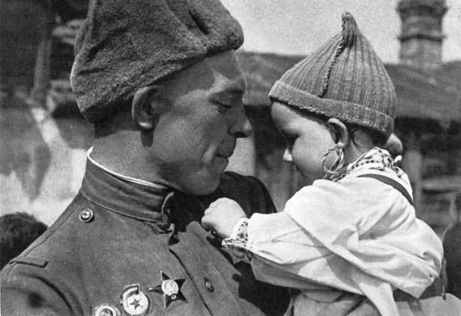 Советский солдат с чешским ребенком на руках. Малыш рассматривает орден Славы на груди бойца. Прага, май 1945 г.