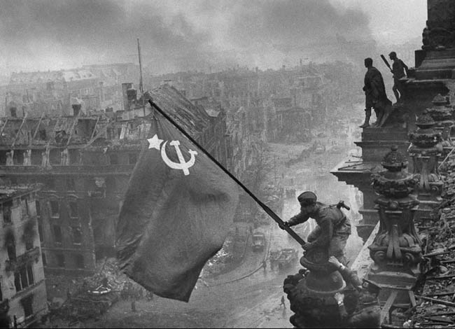 Фотография советского солдата, водружающего над взятым Рейхстагом красное знамя